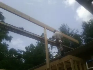 Carpenter setting a ridge beam over a new addition frame — Ice Dam Removal by Roofing Brothers in Ramseur
