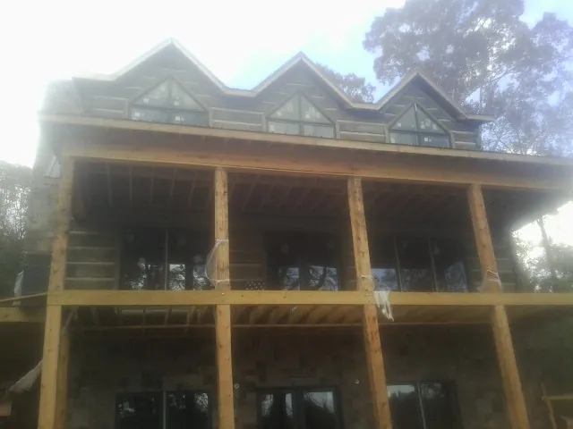 Dormers and porch framing on a large log home under construction — Roof Coating work by our crew in Ramseur