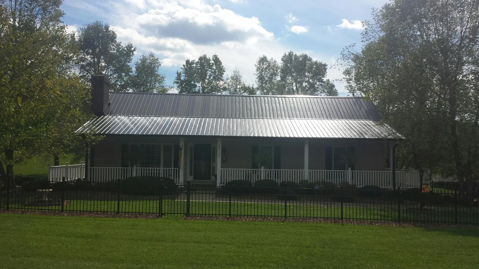 Gray metal roof on a brick ranch with a full width front porch — Gutter Guard Installation work by our crew in Ramseur