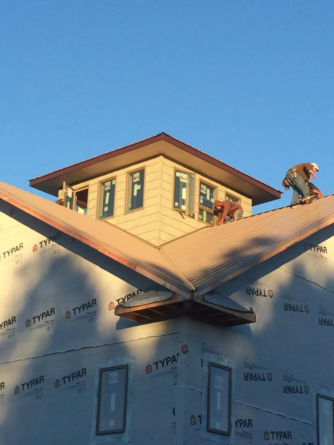 Roofers working around a rooftop cupola on a new metal roof at sunset — Roof Waterproofing in Ramseur by Roofing Brothers